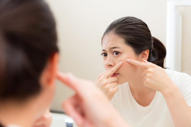 woman checking for acne on face